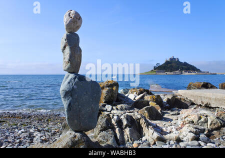 Balancing Steine am Strand von Marazion, Cornwall mit St. Michael's Mount im Hintergrund - Johannes Gollop Stockfoto