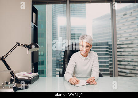 Porträt einer stilvollen Junge weibliche Spezialist mit Gläsern am Tisch sitzen. Psychologe, Anwalt, Banker, Konzept Manager. Stockfoto