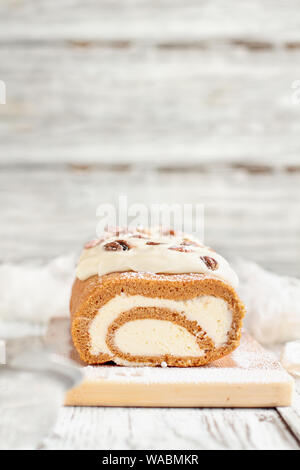 Schöne frische gebackene pumpkin Spice roll Kuchen mit Puderzucker, Pekannüsse, Frischkäse füllen und Vereisung. Extreme selektiven Fokus mit Backgr verschwommen Stockfoto