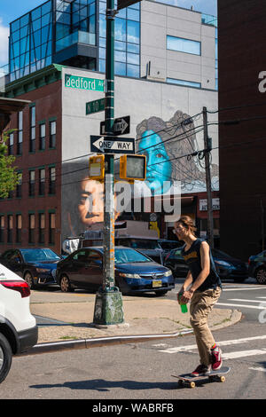 New York Street, im Sommer Blick auf einen jungen Menschen, der ein Skateboard in der Bedford Avenue in Williamsburg, Brooklyn, New York City, USA, fährt Stockfoto