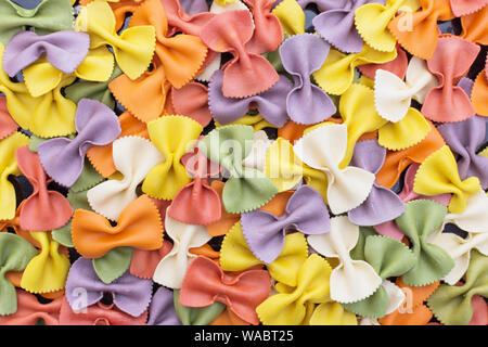 Italienische raw Bunte farfalle Pasta close-up, Textur Wirkung. Bunte Nudeln in Bow Tie Form. Italienische Küche Konzept. Stockfoto