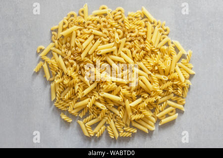 Stapel der Pasta verschiedener Art Draufsicht auf grauem Hintergrund. Viele verschiedene Arten von Pasta, italienische Küche. Stockfoto