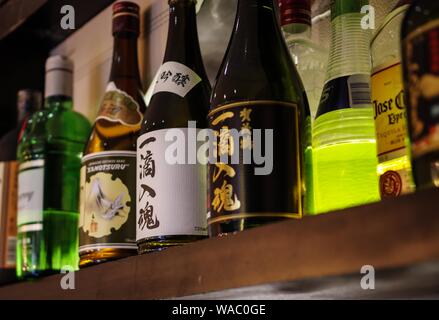 Shanghai, China - Dec 12, 2015: Kamotsuru Itteki Nyukon Sake und Tanqueray Gin Flaschen auf Holz Regal Stockfoto