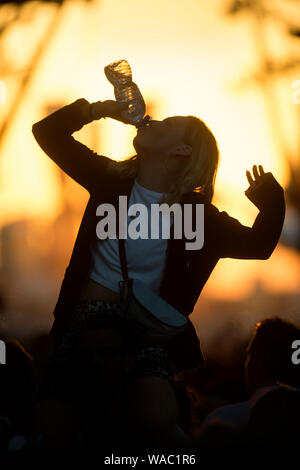 Mädchen Trinkwasser beim Tanzen auf dem Glastonbury Festival 2019 in Pilton, Somerset Stockfoto