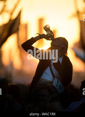 Mädchen Trinkwasser beim Tanzen auf dem Glastonbury Festival 2019 in Pilton, Somerset Stockfoto