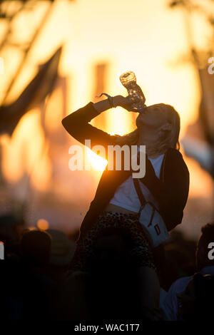 Mädchen Trinkwasser beim Tanzen auf dem Glastonbury Festival 2019 in Pilton, Somerset Stockfoto