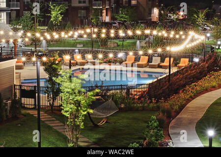 Beleuchtetes Schwimmbad in einem Apartment-komplex in der Nacht Stockfoto