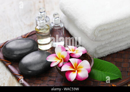 Tropical Spa Resort Konzept; Plumeria, heiße Steine, Handtücher und Massage Öle Stockfoto