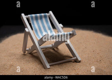 Isolierte Sonnenbank Spielzeug verlegt auf Sand auf schwarzem Hintergrund Stockfoto