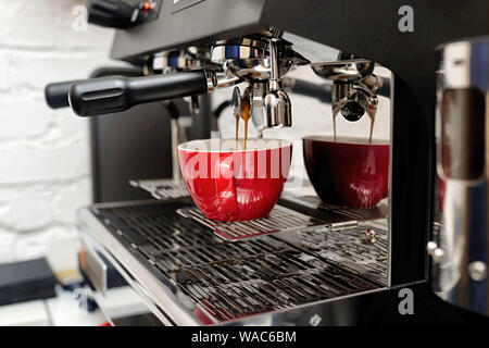 Kaffeemaschine bereitet frischen Kaffee und Red cups im Restaurant, Bar oder Kneipe zu gießen. Stockfoto