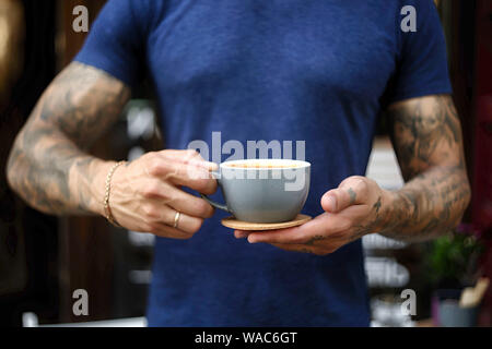 Nahaufnahme des Menschen, die Kaffee im stehen im Café serviert. Fokus auf männliche Hände Inverkehrbringen Zähler eine Tasse Kaffee. Stockfoto
