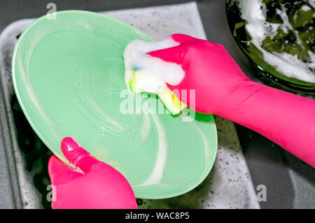 Der Prozess der Waschmaschine Teller in die Spüle, Hände und Platten Nahaufnahme. Waschmittel schäumt. Reinigung Stockfoto