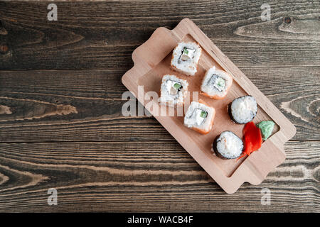 Drei verschiedene Arten von japanischen Rollen mit Wasabi und Ingwer auf Bambus tablett auf schönen hölzernen Hintergrund Stockfoto