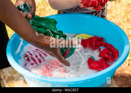 Nanyuki, Kenia - 13. Juni 2019: Farbfoto des kenianischen Frau hand Wäsche waschen in blauer Schüssel mit nur Hände sichtbar. Stockfoto