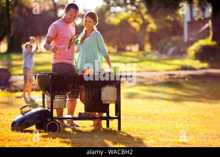 Lächelndes Paar kochen auf einem Grill in Ihrem Hinterhof. Stockfoto