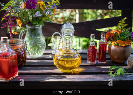 Flaschen des Borretsch und Johanniskraut Öl, mit frischen Kräuter und Blumen im Hintergrund Stockfoto