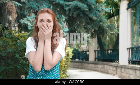 Lächelnd schöne rothaarige Frau bedeckt Mund mit Lachen. Ingwer sommersprossiges Mädchen lacht an Witz. Cute funny Rothaarige Teenager mit kopieren. Stockfoto