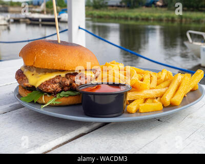 Leckeres Rindfleisch Burger mit Salat Garnituren, Cheeseburger auf einem Holzbrett outdoor mit schöner Aussicht Stockfoto