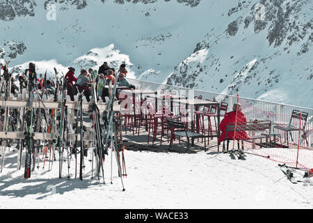 Pyrenäen, ANDORRA - Februar 13, 2019: Unbekannter Touristen zu einem Skigebiet in einem Cafe an der Seite eines Berges. Sonnigen Tag Winter, Gartenstühle und Tabl Stockfoto