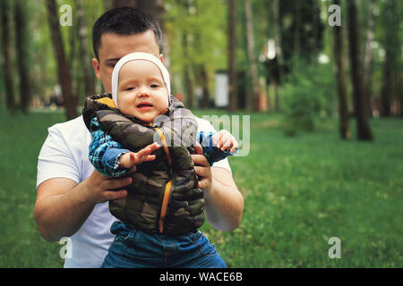 Füße Jahr alten Sohn und Vater auf dem Gras. Vati lehrt das Kind zu gehen. Jeans und Turnschuhe. Vaterschaft Stockfoto