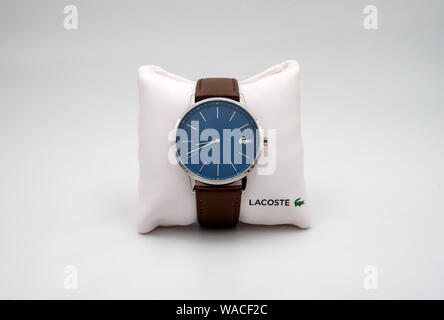 PARIS, Frankreich, 19. AUGUST 2019: Lacoste Armbanduhr mit dunkelblauem Ziffernblatt und Band aus braunem Leder zu einem kleinen Kissen befestigt. Stockfoto