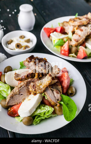 Close-up von gegrilltem Fleisch und Salat mit Gemüse, Mozzarella und Kräutern. Traditionelle mediterrane Küche Stockfoto