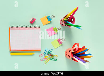 Ansicht von oben in Notepad und bunten Schulmaterial auf grünem Hintergrund Stockfoto