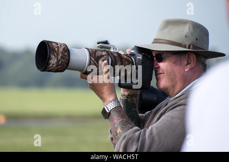 Ein Mann fotografieren mit super großen Linse in camaflouge abgedeckt (EDITORIAL NUR VERWENDEN) Stockfoto