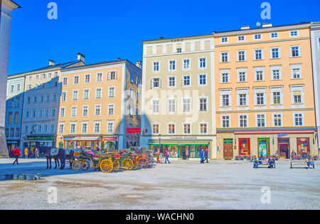 SALZBURG, Österreich - 27. FEBRUAR 2019: Die Linie der mittelalterlichen Häuser mit Geschäften und Cafés mit Blick auf den großen Residenzplatz, am 27. Februar in Salzburg. Stockfoto