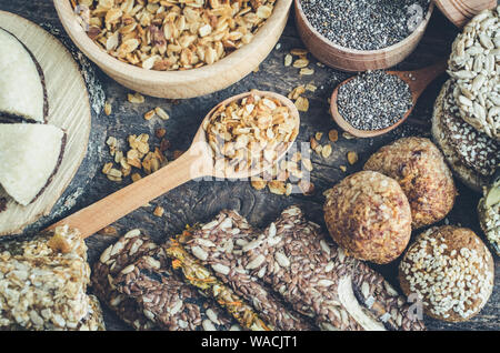 Gesunde Snacks. Diätetische Lebensmittel. Sesam Halva. Flocken, Chia Samen in zwei Schüsseln und Löffel. Kozinaki, drei Müsliriegel. Die Grissini mit Flachs, sunfl Stockfoto