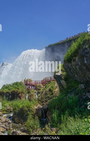 Niagara Falls, NY: Touristen in gelbe Regenmäntel genießen Sie die Höhle der Winde, Treppen und Plattformen am Fuße des American Falls, auf Goat Island. Stockfoto