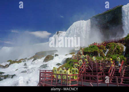 Niagara Falls, NY: Touristen in gelbe Regenmäntel genießen Sie die Höhle der Winde, Treppen und Plattformen am Fuße des American Falls, auf Goat Island. Stockfoto