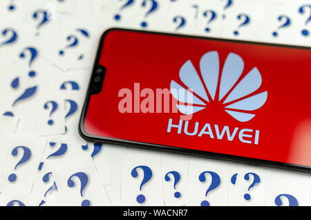 HUAWEI HUAWEI Logo auf dem Smartphone und eine Menge Papier Fragezeichen um. Die konzeptuellen Foto über Zukunft der Tech giant in den USA. Stockfoto