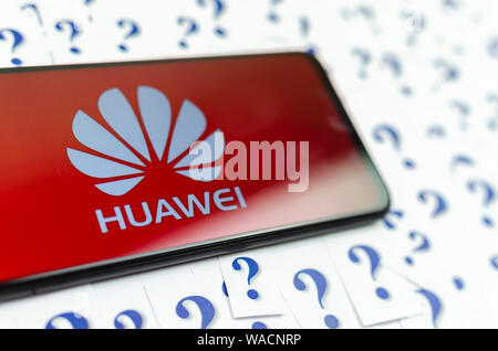 HUAWEI HUAWEI Logo auf dem Smartphone und eine Menge Papier Fragezeichen um. Die konzeptuellen Foto über Zukunft der Tech giant in den USA. Stockfoto