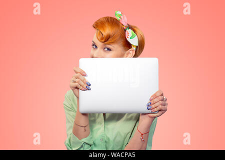 Student versteckt sich hinter Laptop. Closeup Portrait headshot Schöne nette junge geschäftsfrau Pinup girl Holding Übersicht Computer auf Pfirsich isolierte Rosa Stockfoto