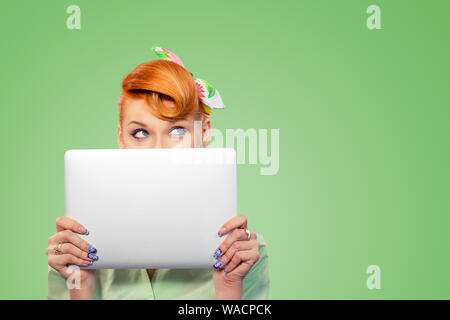 Student versteckt sich hinter einem Laptop. Closeup Portrait headshot schönen selbstbewussten jungen Geschäftsfrau pinup Girl holding Computer isoliert auf Grün backgr Stockfoto