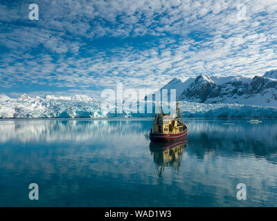 Ein Schiff fährt auf einem flachen See, in der Ferne ein Gletscher Stockfoto