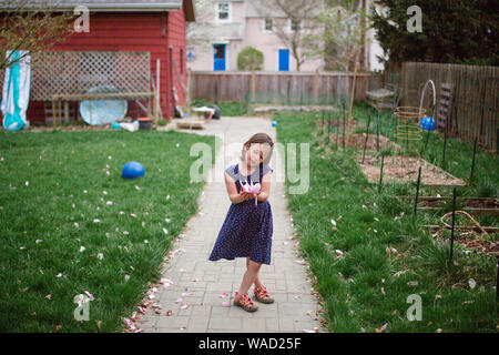 Ein kleines Mädchen bewundert eine große rosa Blume in Ihren Händen Stockfoto