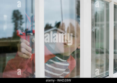 Porträt der Jungen spielen mit einem Flugzeug in das Fenster zu Hause Stockfoto