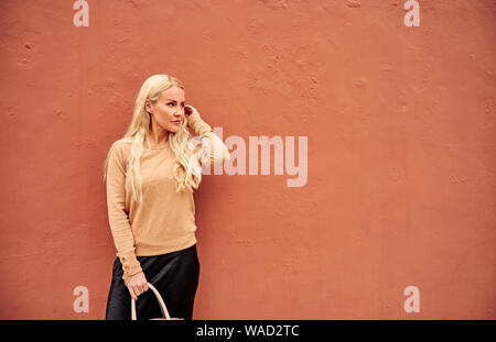 Schöne Frau von orange Wand-, Richt lange Haare und Wegsehen in Teneriffa auf Tagfahrlicht Stockfoto