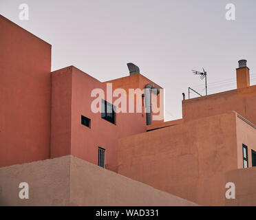 Von unten orange und rosa Häuser unterschiedlicher Höhe auf weißem Himmel Hintergrund in Teneriffa. Stockfoto