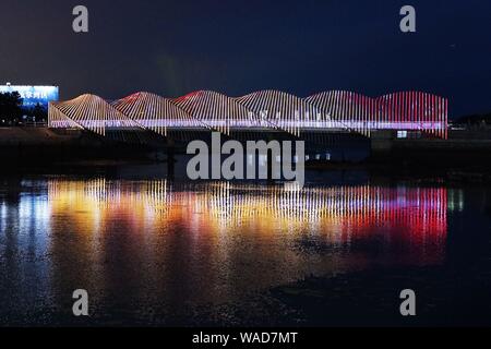 Anwohner Spaziergang auf der Regenbogenbrücke von bunten Lichtern in Qingdao Stadt beleuchtet, der ostchinesischen Provinz Shandong, 27. Juli 2019. Stockfoto