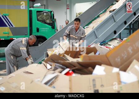 Ein chinesischer Arbeiter sortiert Recycling Abfall, der auf einer Distribution Center der erneuerbaren Energien Abfälle aus Behälter bereitgestellt werden, um das neue Müll sortieren s gerecht zu werden gesammelt Stockfoto