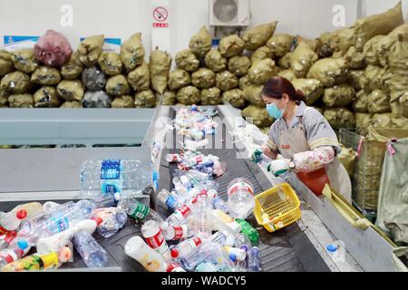 Ein chinesischer Arbeiter sortiert Recycling Abfall, der auf einer Distribution Center der erneuerbaren Energien Abfälle aus Behälter bereitgestellt werden, um das neue Müll sortieren s gerecht zu werden gesammelt Stockfoto