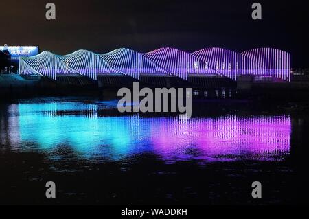 Anwohner Spaziergang auf der Regenbogenbrücke von bunten Lichtern in Qingdao Stadt beleuchtet, der ostchinesischen Provinz Shandong, 27. Juli 2019. Stockfoto