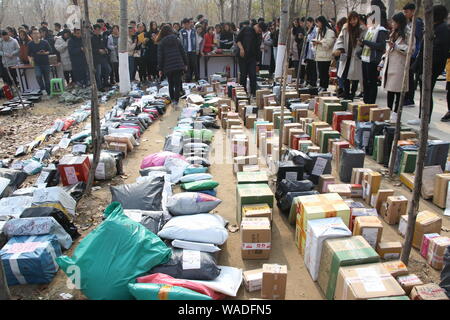 ------ Chinesische Studenten suchen in einer Masse von Parzellen, von denen die meisten von Singles online einkaufen, auf einem Pickup - Station einer Universität in Binz Stockfoto