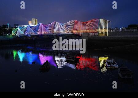 Anwohner Spaziergang auf der Regenbogenbrücke von bunten Lichtern in Qingdao Stadt beleuchtet, der ostchinesischen Provinz Shandong, 27. Juli 2019. Stockfoto