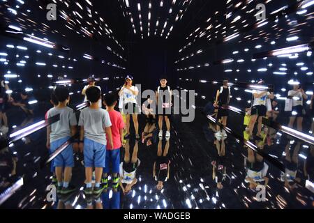 Chinesische Eltern und ihre Kinder zu Fuß durch die "Time Tunnel", die während des interaktiven Wissenschaft Ausstellung "Hawking und George's Universum' in Changsha ci Stockfoto