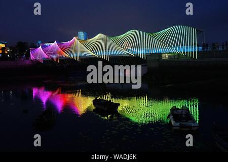 Anwohner Spaziergang auf der Regenbogenbrücke von bunten Lichtern in Qingdao Stadt beleuchtet, der ostchinesischen Provinz Shandong, 27. Juli 2019. Stockfoto