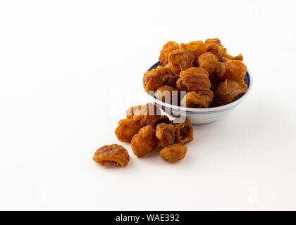 Gruppe von Getrocknetes longan Früchte in Schale und auf weißem Hintergrund Stockfoto